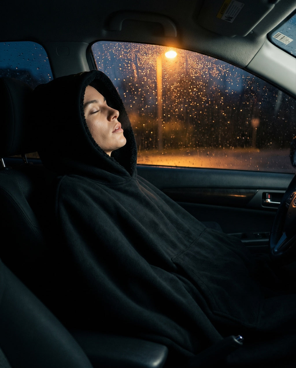 The Exhale in Obsidian, worn reclined in a parked car at night, rain on the glass